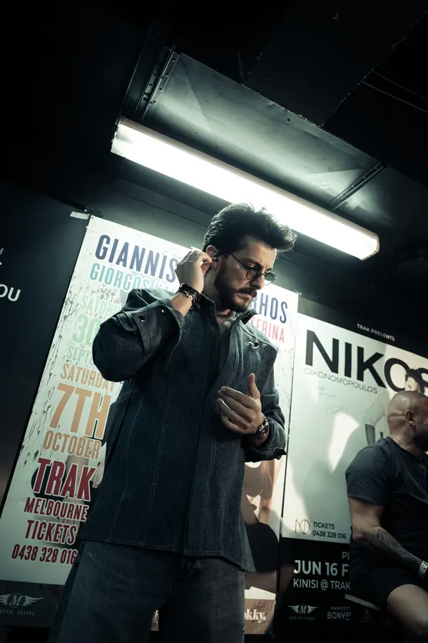 Andre Soueid wearing a denim jacket backstage in front of concert posters